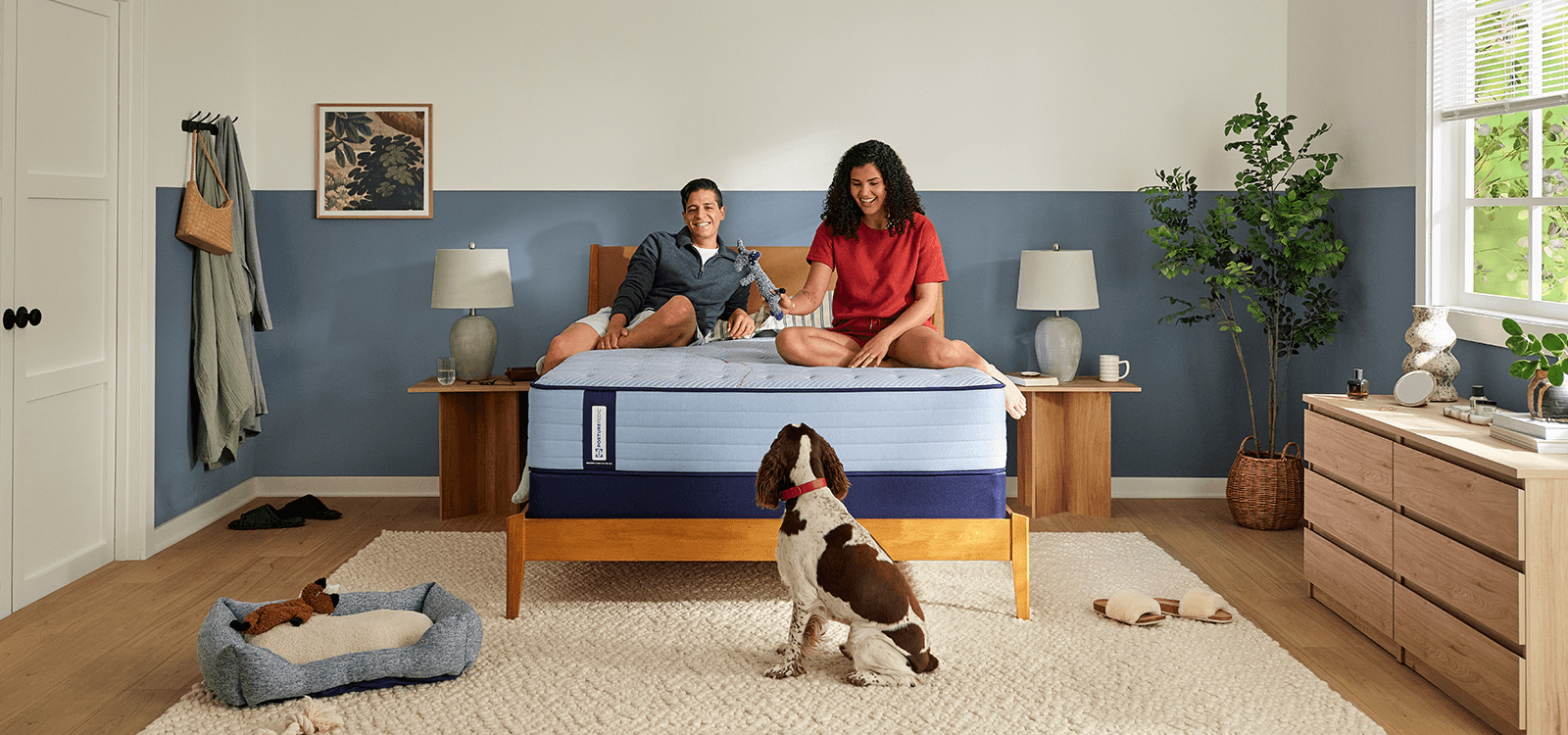 Couple laying on a Posturepedic Spring mattress playing with dog