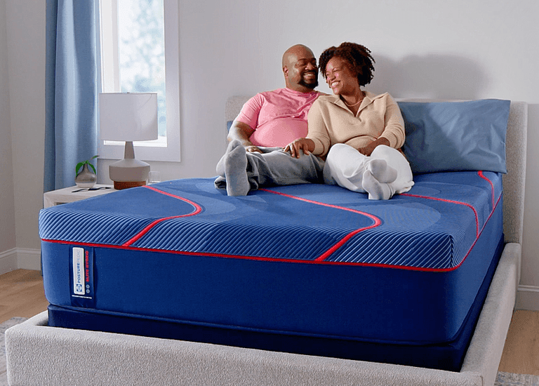 Man and woman laying on a Posturepedic Elite Hybrid mattress in a styled room