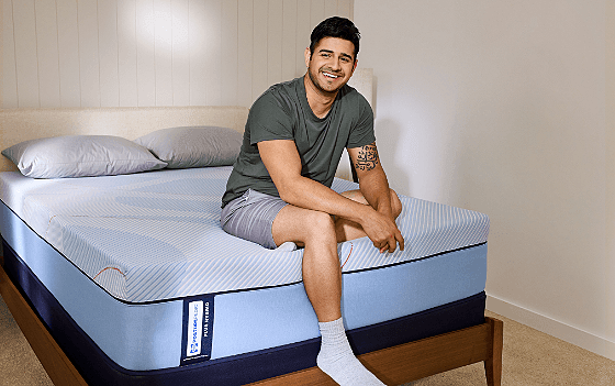 Man sitting on Posturepedic Plus Hybrid mattress