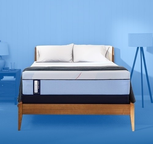 Posturepedic Plus mattress in a styled room with a blue background